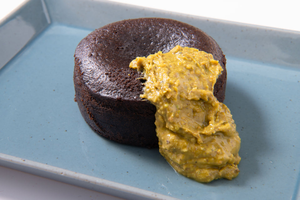 ホワイトチョコレートピスタチオバターをトッピングした、ガトーショコラの写真